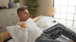 © Krakenimages.com - Middle-aged man sitting on bed in bedroom at home, morning awakening in comfortable interior with white pillows and striped pajamas, matching modern decor