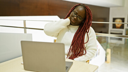 Sticker - African american woman with braids feeling neck pain at her office desk.