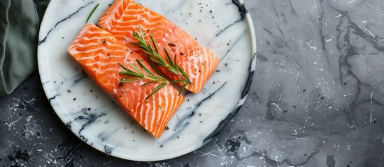 Poster - Top view of a rosemary seasoned salmon fillet on a marble plate perfect for making a delicious salmon steak with a copy space image included