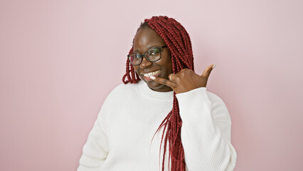 Sticker - Smiling black woman with red braids making call-me gesture against a pink background.