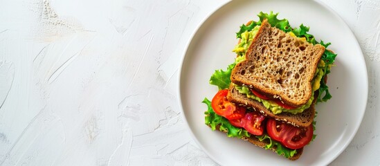 Poster - A sandwich with guacamole and heirloom tomato on wheat bread displayed on a white plate against a white background with copy space image