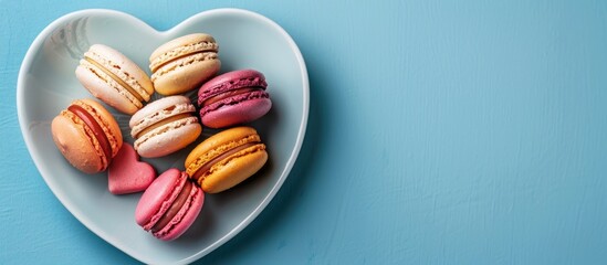 Wall Mural - A Valentine s Day card featuring macaroons on a heart shaped plate against a blue background displayed from above with copy space image