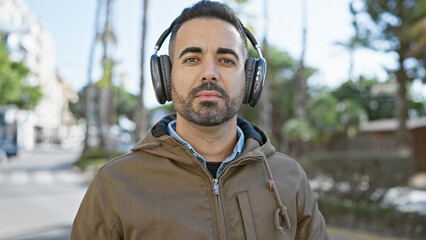 Canvas Print - Handsome hispanic man with beard wearing headphones on an urban street