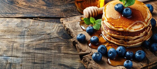 Poster - A tempting display of pancakes topped with honey and blueberries on a wooden backdrop offering copy space image