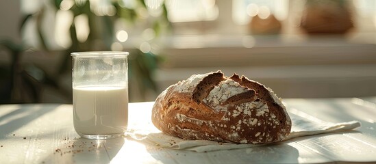 Poster - Copy space image of sunlight illuminating rye bread on white wood beside a glass of milk