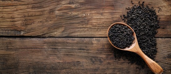 Poster - Wooden spoon holding dried black tea leaves displayed on a wooden table with copy space image available