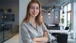 © JINGWEN - Confident businesswoman with crossed arms smiling in modern office, facing camera, embodying success in professional attire with sleek hairstyle.