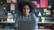 © keetazalay - A young African American teacher working on a laptop in a modern classroom, surrounded by educational materials and digital tools, demonstrating the integration of technology in teaching and the
