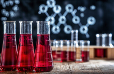 Poster - Three flasks containing red chemical liquid on a table in a chemistry laboratory with a blackboard background with copy space