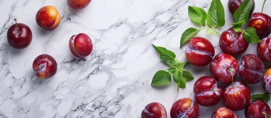 Delicious ripe plums on a white marble table top view Area for text. with copy space image. Place for adding text or design