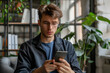 © La Neve - Young Man Using Smartphone in Indoor Greenery Environment