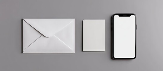 Poster - Top view of a white envelope a blank card and a smartphone with a blank screen all set against a grey background. with copy space image. Place for adding text or design
