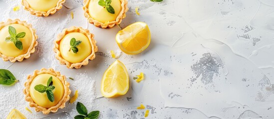 Homemade lemon tartlets on a white and grey concrete backdrop with a copy space image.