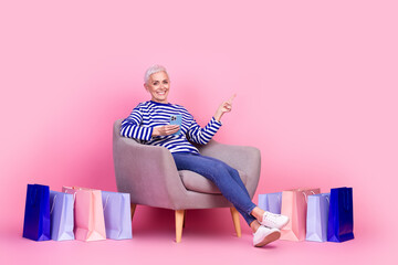 Canvas Print - Photo of charming attractive woman wear striped stylish clothes sit armchair recommend empty space isolated on pink color background