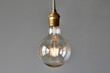 © ylivdesign - Round led lightbulb is shining brightly while hanging on a gray background