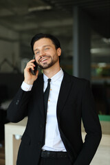 Wall Mural - A man in a suit is talking on his cell phone while smiling. He is dressed professionally and he is in a good mood