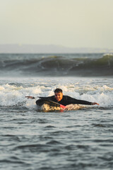 Young man riding a wave lying on his surfboard