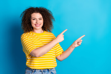 Wall Mural - Photo portrait of attractive young woman point cheerful empty space dressed stylish striped yellow clothes isolated on blue color background