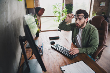Portrait of professional hacker young man stare screen computer desk loft interior office indoors