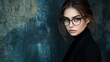 © Iswanto - Close-up portrait of a beautiful young woman with dark hair, wearing round glasses and a black turtleneck, looking directly at the camera.