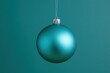 © volga - Shiny teal Christmas ornament on green background
