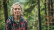 © nopommajun - A woman in a flannel shirt, with a backpack, hiking in a lush forest trail, enjoying the beauty and tranquility of nature.