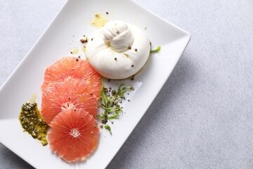 Wall Mural - Delicious burrata cheese, grapefruit and spices on light grey table, top view. Space for text