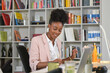 © ADDICTIVE STOCK CORE - Smiling black woman taking notes in notebook in office