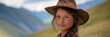 © nopommajun - A young girl wearing a hat poses in a scenic mountainous backdrop, with the landscape stretching out behind her and a calm expression.