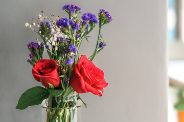 Poster - A bouquet of fresh roses with baby breath in a glass water jar on white background.