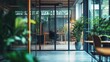© Bonsales - Blurred image of a modern office interior with glass walls, stylish furniture, and lush green plants creating a tranquil and productive workspace