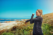 © SensSai/peopleimages.com - Fitness, thinking and stretching with woman outdoor on mountain for summer, exercise and health. Wellness, training and warm up with female athlete on coast for running, workout and morning cardio