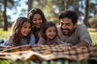 © fotofabrika - Family enjoying a picnic on a sunny day in the park with laughter and joy among two children and their parents