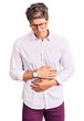 © Krakenimages.com - Young handsome man wearing business clothes and glasses with hand on stomach because indigestion, painful illness feeling unwell. ache concept.