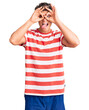 © Krakenimages.com - Young handsome man wearing casual clothes doing ok gesture like binoculars sticking tongue out, eyes looking through fingers. crazy expression.
