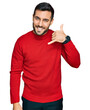 © Krakenimages.com - Young hispanic man wearing casual clothes smiling doing phone gesture with hand and fingers like talking on the telephone. communicating concepts.