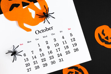 Wall Mural - Calendar 31st of October date. Halloween background, planning party. Flat lay. Top view photo of calendar, Halloween decorations pumpkins, spiders on black and orange background.