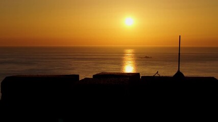 Wall Mural - Drone ascending to reveal a fiery orange sunset over Mediterranean Sea in Nigran, Spain