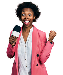 Canvas Print - African american woman with afro hair holding reporter microphone screaming proud, celebrating victory and success very excited with raised arms