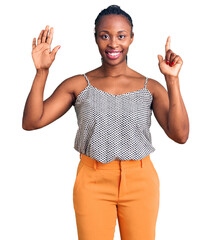 Sticker - Young african american woman wearing casual clothes showing and pointing up with fingers number seven while smiling confident and happy.