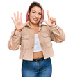 © Krakenimages.com - Hispanic woman with pink hair wearing casual clothes showing and pointing up with fingers number seven while smiling confident and happy.