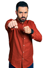 Poster - Young hispanic man with beard wearing casual shirt punching fist to fight, aggressive and angry attack, threat and violence