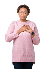 Wall Mural - Beautiful young african american woman over isolated background smiling with hands on chest with closed eyes and grateful gesture on face. Health concept.