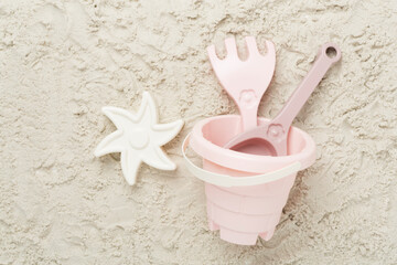 Cute toys for playing on sand background, top view