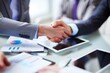 © 为轩 张 - Close-up view of business people shaking hands over a table with documents and digital tablet, symbolizing successful collaboration and professional agreement.