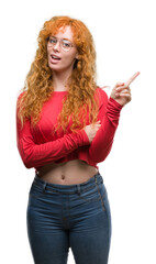 Young redhead woman wearing glasses very happy pointing with hand and finger to the side