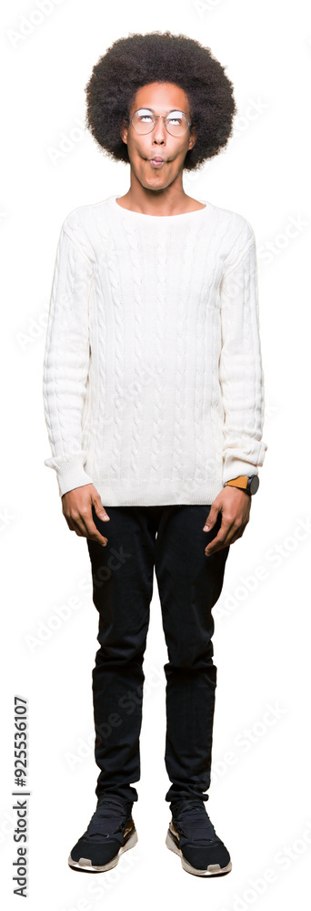 Young african american man with afro hair wearing glasses making fish face with lips, crazy and comical gesture. Funny expression.