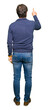 © Krakenimages.com - Middle age handsome man wearing a sweater Posing backwards pointing behind with finger hand