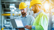 © Катерина Євтехова - Engineers discussing a project in a high-tech manufacturing facility, both wearing safety helmets and using a laptop to review technical details, the bright and modern environment