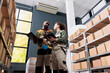 © DC Studio - Diverse storage room workers looking at cardboard boxes, working at goods inventory in storehouse. African american supervisor and employee preparing customers orders for delivery in storehouse